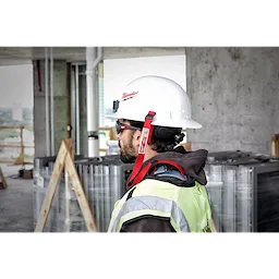 Worker wearing a white hard hat secured with a red Hard Hat Lanyard with Loop, standing at a construction site.