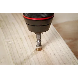 The M2 Steel Screw Extractor Set 4PC is shown in use, with an extractor bit attached to a power drill, removing a damaged screw from a piece of wood. The focus is on the drilling process and the effectiveness of the extractor bit.