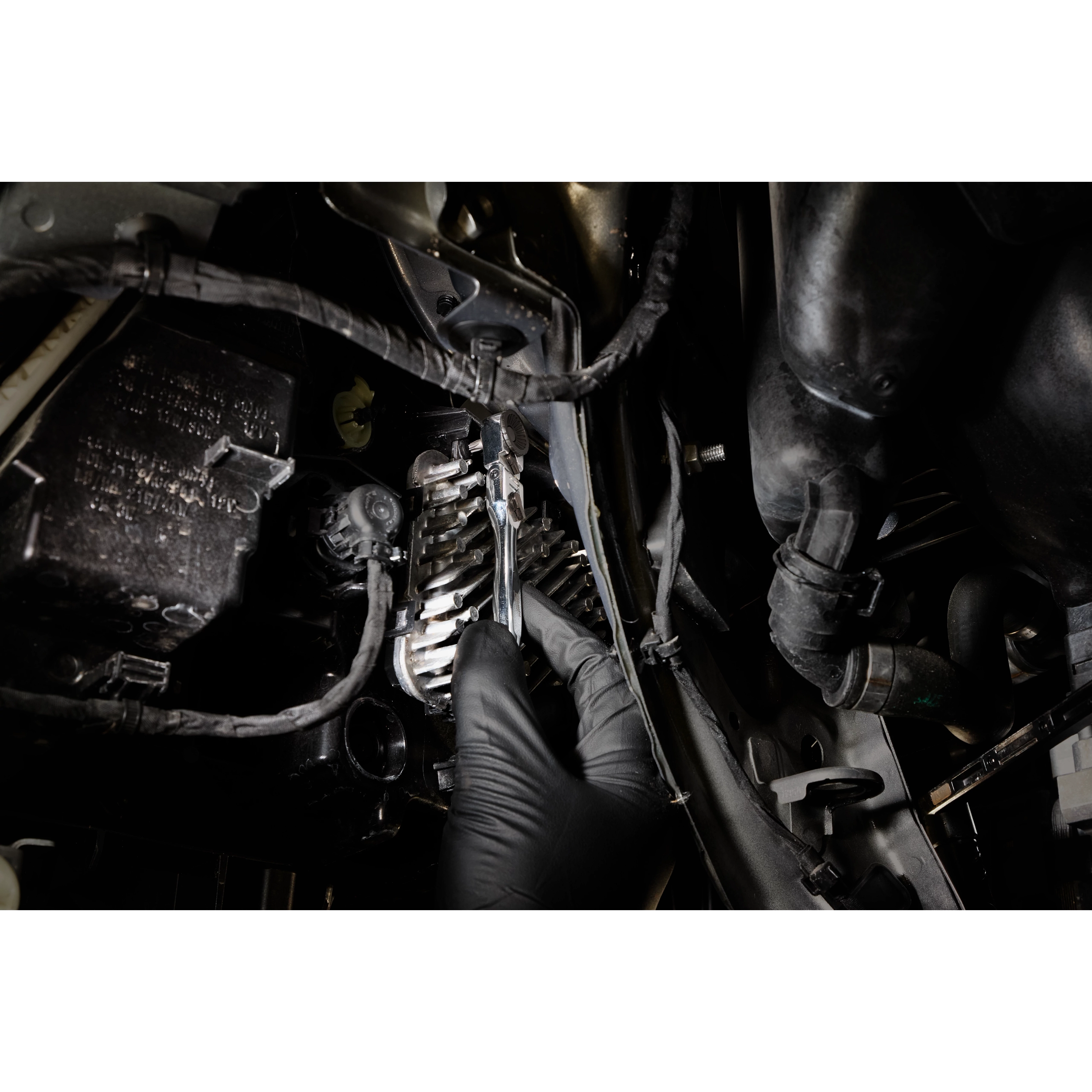 Gloved hand using a 1/4” Hex Drive Mini Flex Head Bit Ratchet in a tight engine compartment.