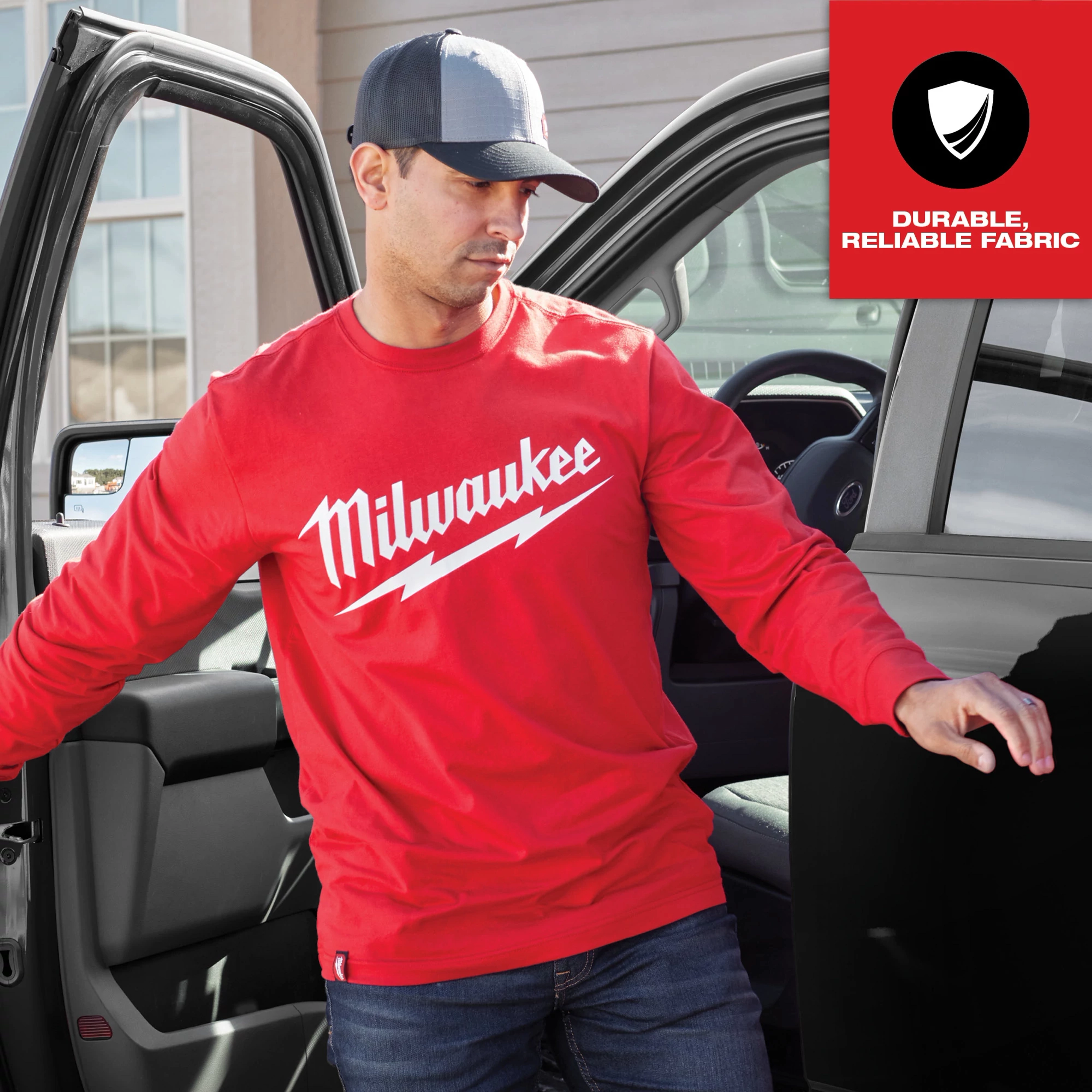 Red Heavy Duty Tee - Long Sleeve Logo Feature Shot with "Milwaukee" logo in white script, worn by a man exiting a vehicle.