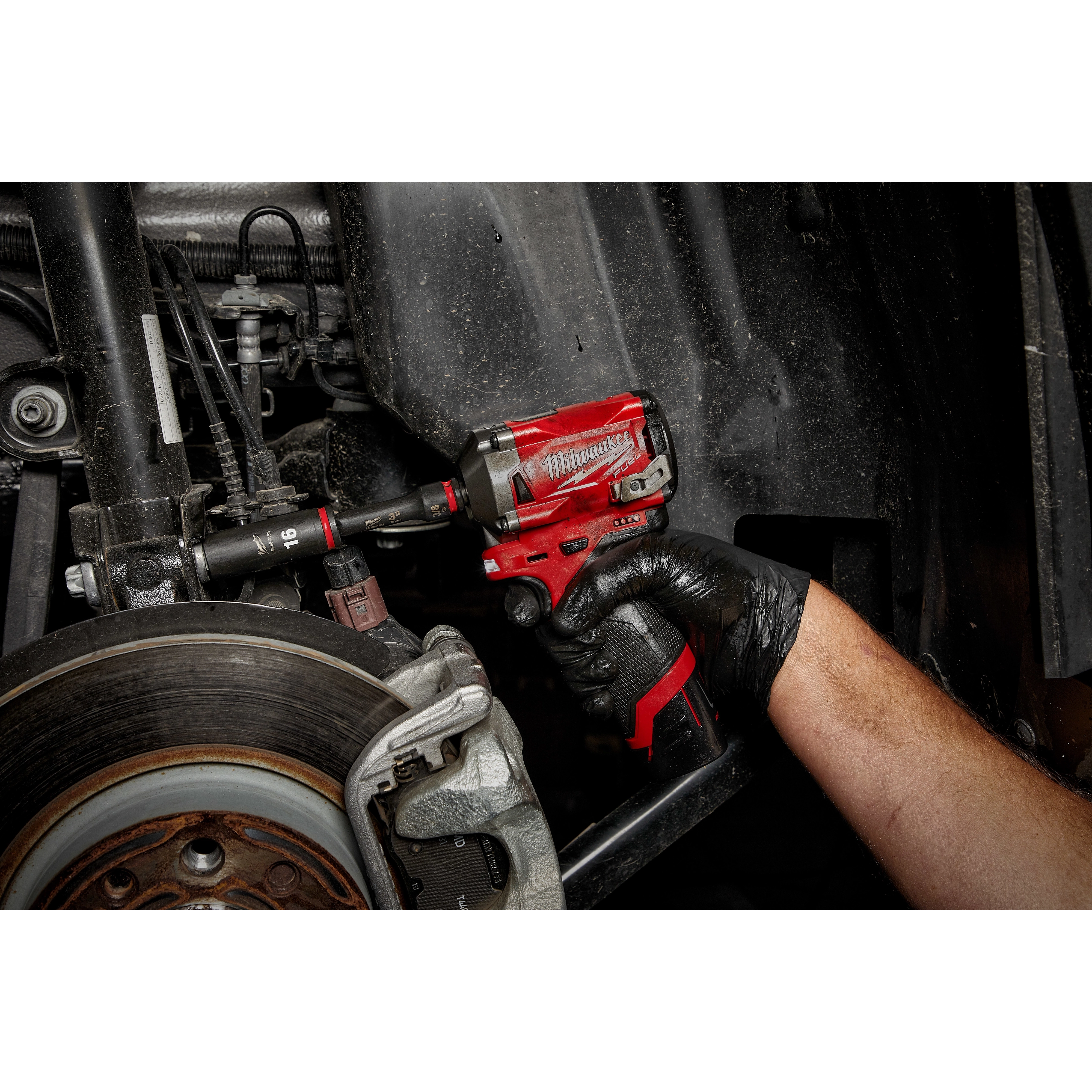 A gloved hand uses a red impact wrench to tighten a bolt on a car part with the SHOCKWAVE Impact Duty 3/8" Drive 16MM Deep 6 Point Socket.