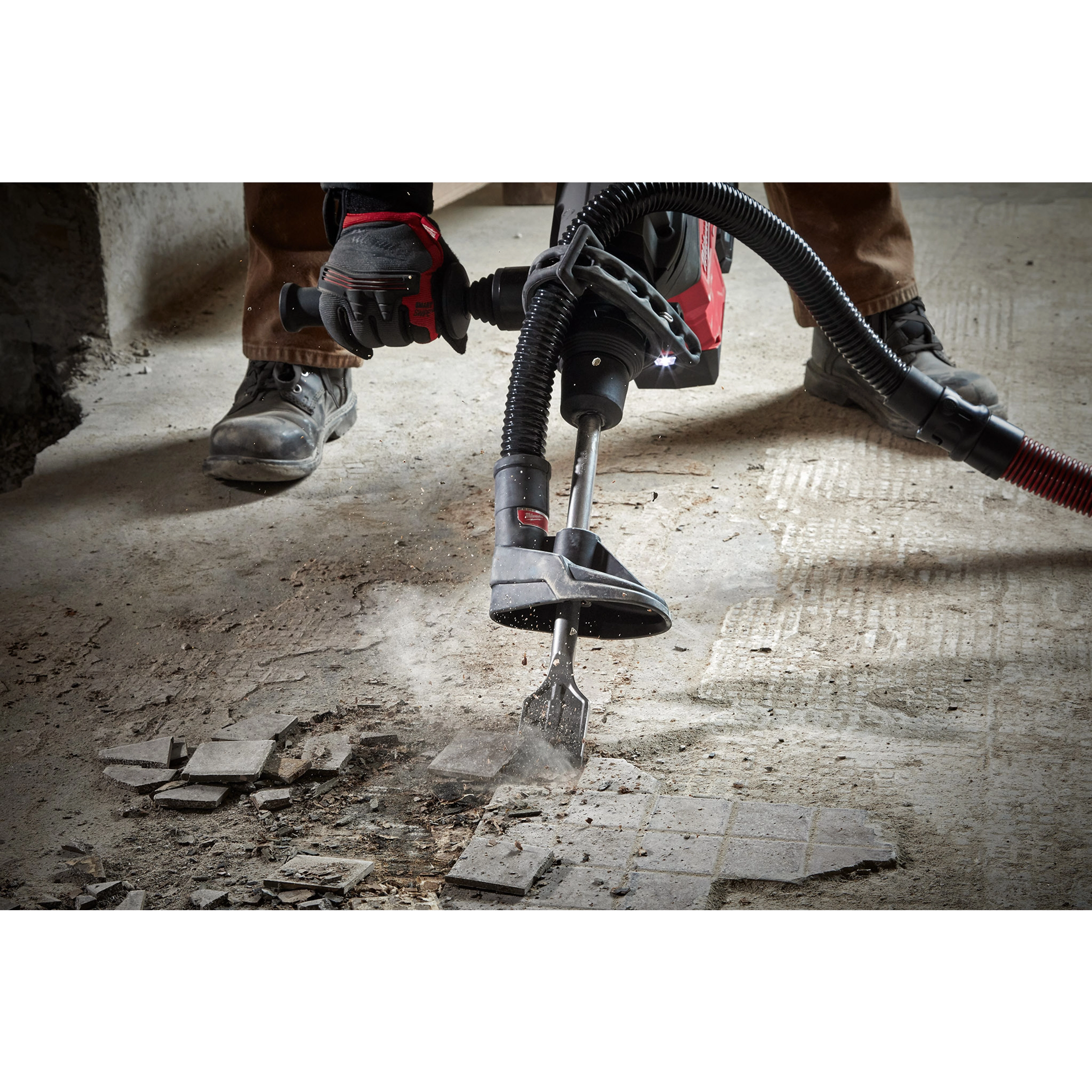 Worker uses SDS-MAX SLEDGE 2" Tile Chisel to remove floor tiles. The tool is attached to a vacuum system, minimizing dust.