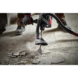 Worker uses SDS-MAX SLEDGE 2" Tile Chisel to remove floor tiles. The tool is attached to a vacuum system, minimizing dust.