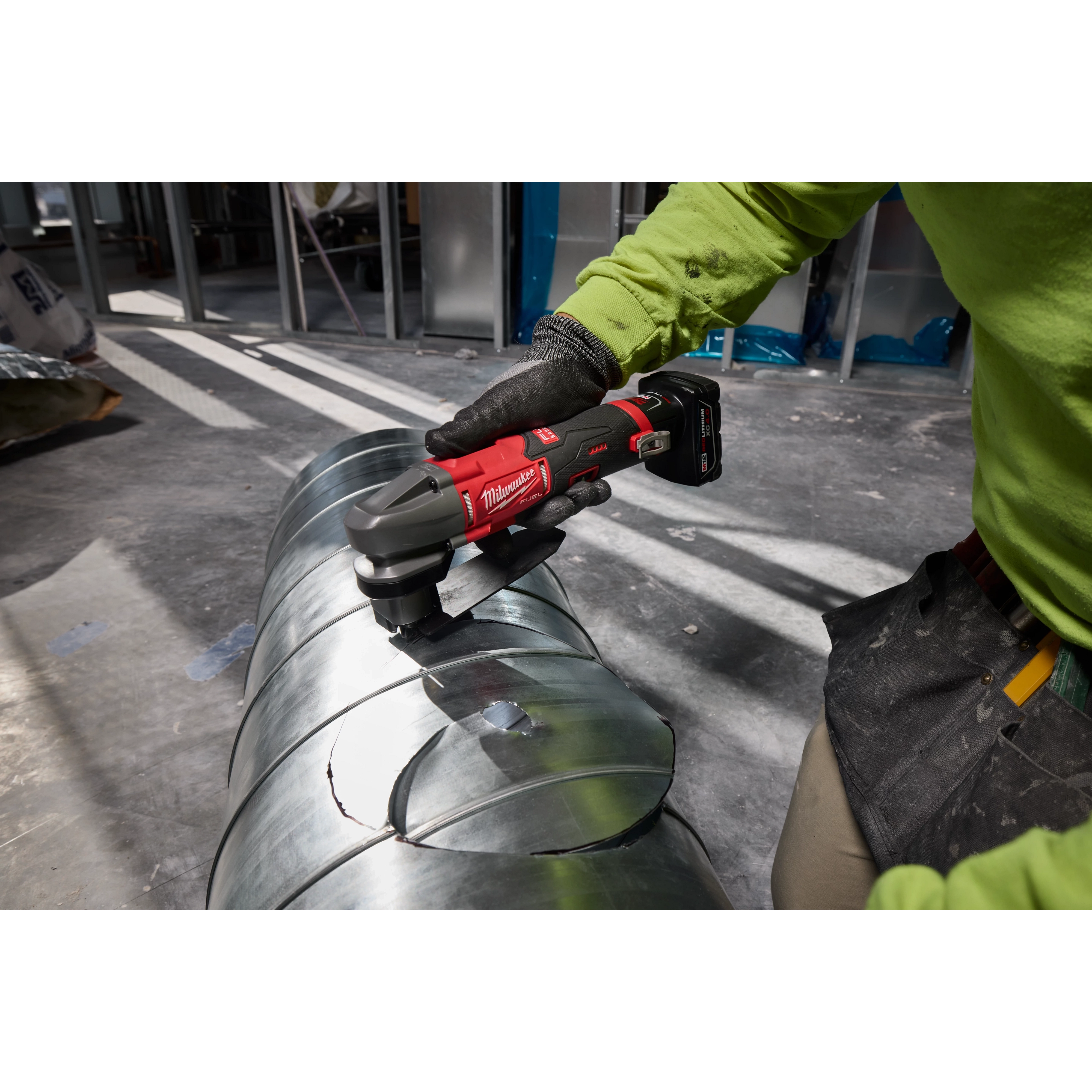 M12 FUEL 16 Gauge Scroll Shear cutting curved shapes into a metal duct on a workshop floor