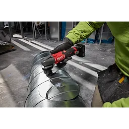 M12 FUEL 16 Gauge Scroll Shear cutting curved shapes into a metal duct on a workshop floor