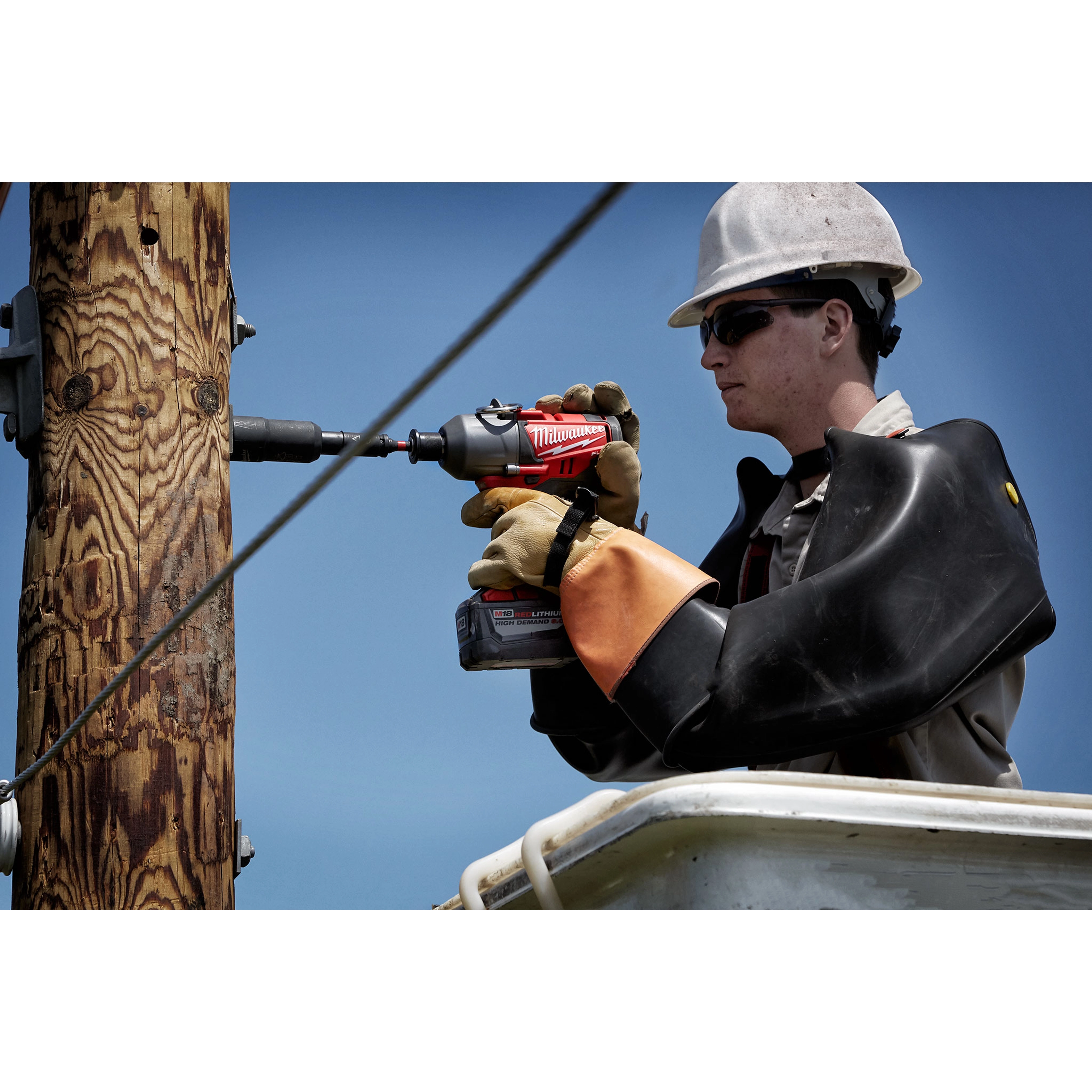 A worker in safety gear uses the Power Utility Socket to drill into a vertical wooden utility pole.
