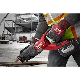 Person wearing Cut Level 3 Winter Insulated Gloves - XL holding a red power tool on a snowy construction site.
