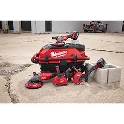 Milwaukee power tools are organized around a red and black vacuum system, branded with the word Milwaukee. The tools include grinders, drills, and saws, part of the DUST SHROUD FAMILY.