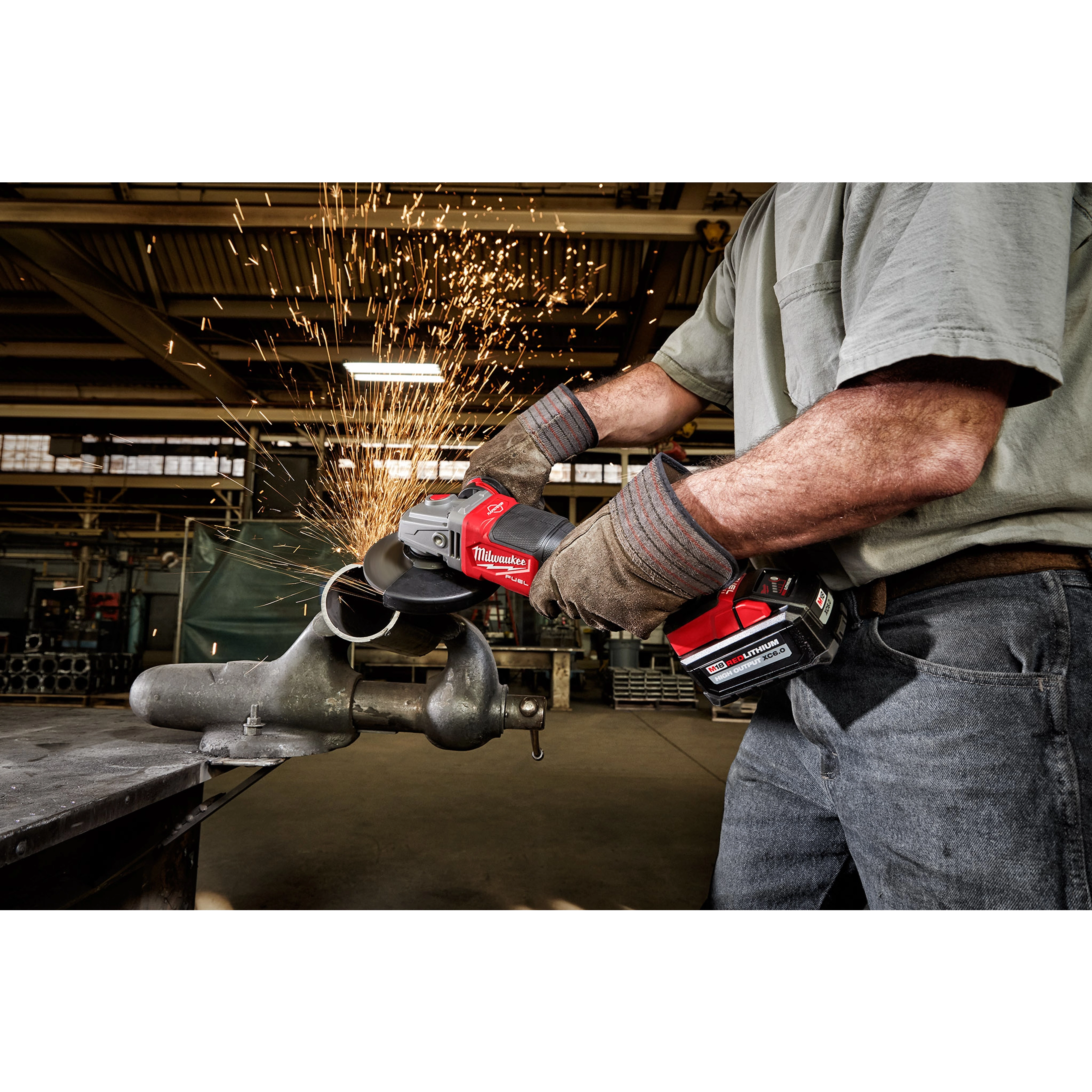 Person grinds metal pipe using M18 FUEL 4-1/2" - 6" Braking Grinder with Paddle Switch, No-Lock. Sparks fly in industrial setting.