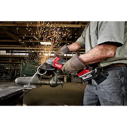 Person grinds metal pipe using M18 FUEL 4-1/2" - 6" Braking Grinder with Paddle Switch, No-Lock. Sparks fly in industrial setting.