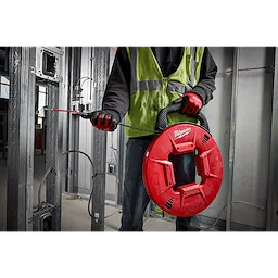 Person using the 200% Polyester Fish Tape w/ Flexible Leader to guide electrical wire through metal framing in a construction site.