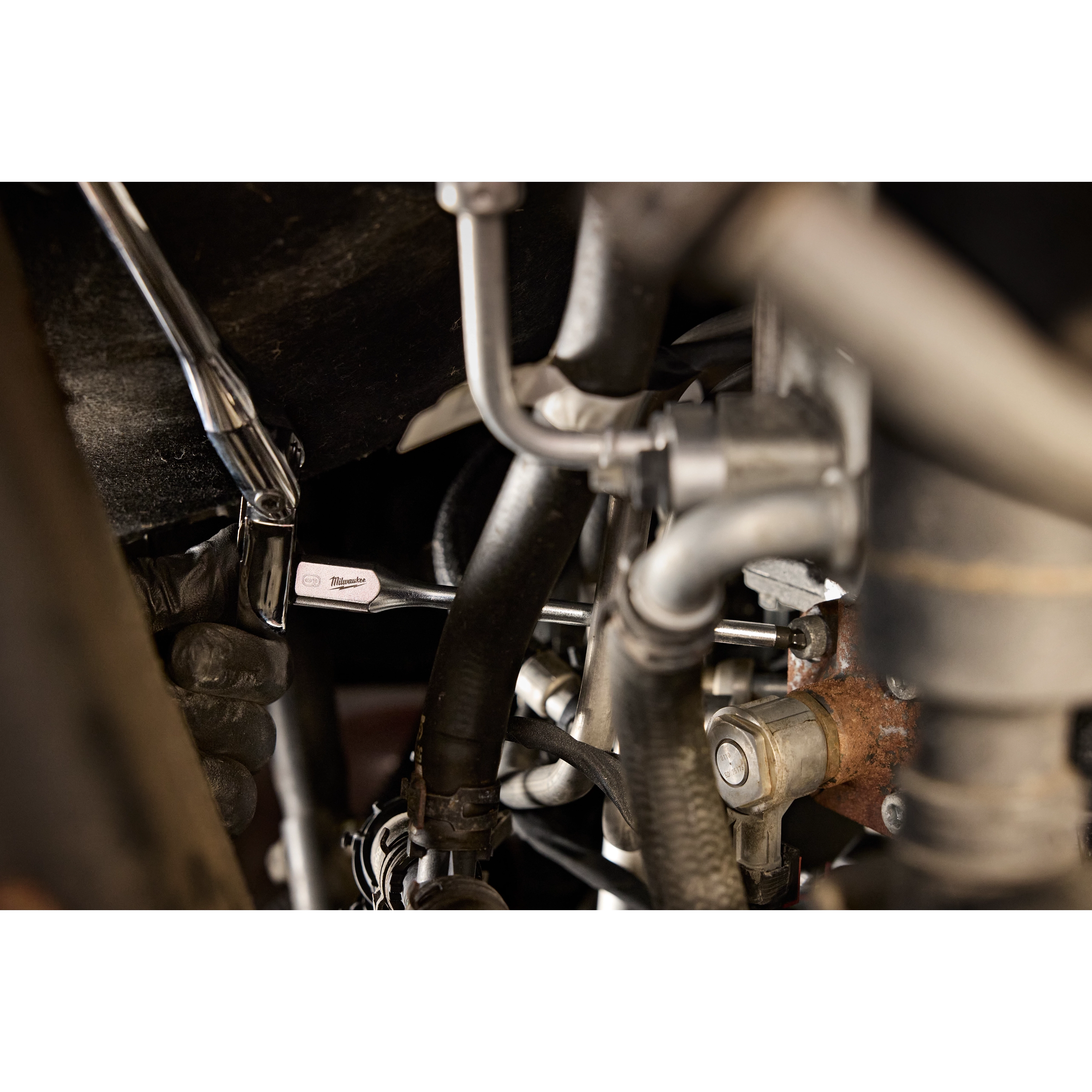 Person uses a 3/8" Drive 6mm Long Ball End Hex Bit Socket to work on machinery with various metal pipes and bolts. The socket appears engaged with a ratchet handle, performing maintenance or assembly tasks.