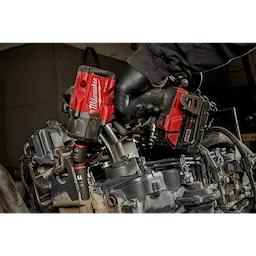 Red Milwaukee Fuel impact wrench using SHOCKWAVE Impact Duty 3/8" Drive 15MM Deep 6 Point Socket on an engine, with a person’s hand.