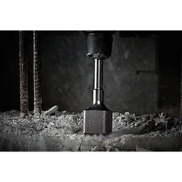 Bushing Tool at work on a concrete surface, chiseling away material. Rebar rods are visible on the left side of the image.