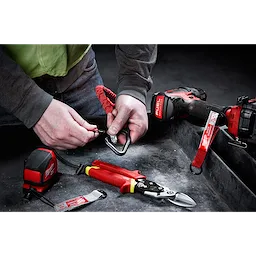 Person using the 10 LB QUICK-CONNECT Locking Tool Lanyard with various red and black tools on a dusty surface.