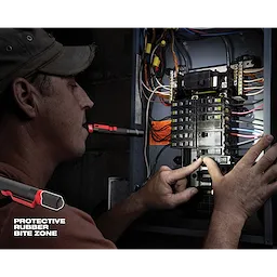 A person uses a Penlight with a protective rubber bite zone while working on an electrical panel.