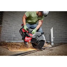Worker in safety gear uses the MX FUEL 14" Cut-Off Saw with RAPIDSTOP, creating sparks while cutting metal rebar on the ground.
