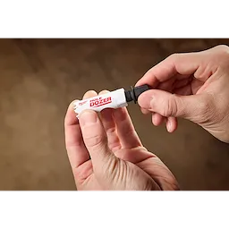 A person is holding a 5PK Small Adapter for QUIK-LOK™ Arbor in their hands. The adapter is labeled "HOLE DOZER" in red and white colors and has a threaded end for attachment.