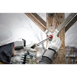 Lineman uses the Lineman's 5-in-1 Ratcheting Wrench to tighten a bolt on a wooden utility pole, wearing safety gloves and helmet.
