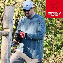 Worker wearing the FREEFLEX Hybrid Work Tee - Long Sleeve, using a power tool outdoors with a text overlay: "Engineered to move freely on the job."