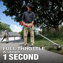 Worker using M18 FUEL String Trimmer w/ QUIK-LOK Kit along a paved driveway.