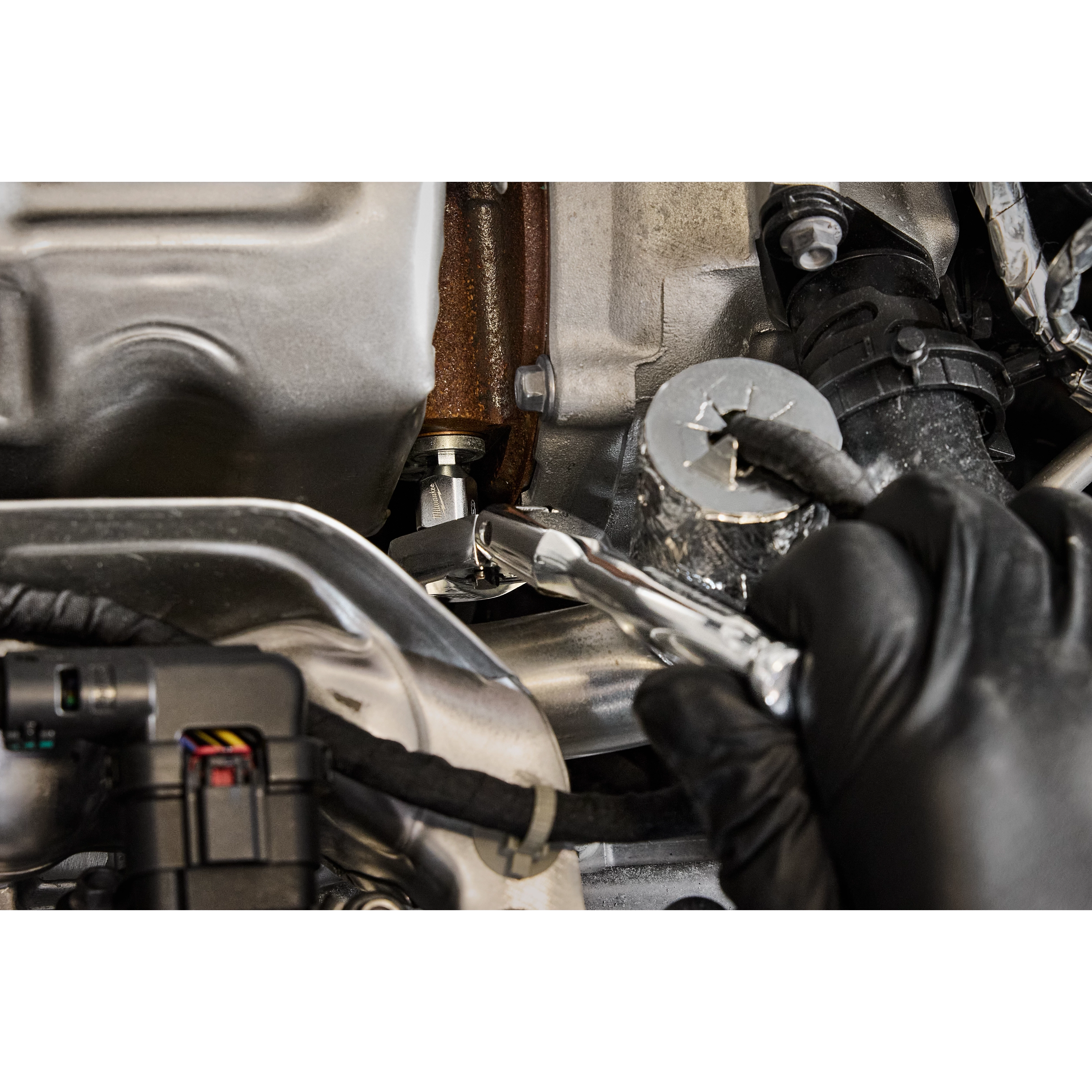 A gloved hand uses a 1/4" Drive 6mm Low-Profile Hex Bit Socket to tighten or loosen a bolt in a compact space within an engine compartment. The socket is attached to a ratchet, facilitating precise adjustments.