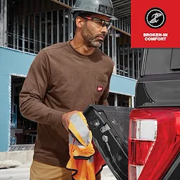 Man wearing the GRIDIRON Pocket Long Sleeve T-Shirt, working at a construction site with a truck in the background.
