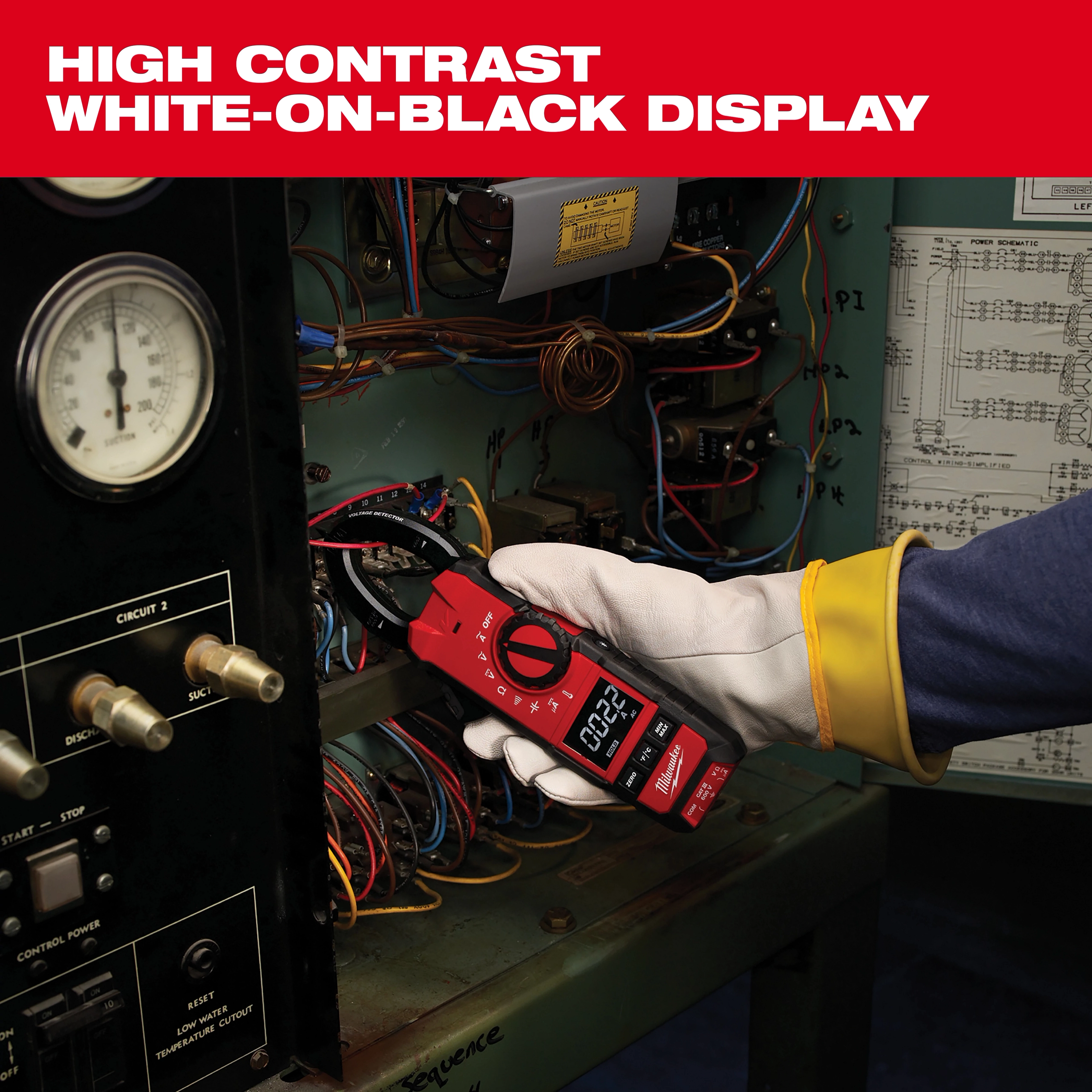A person uses a Milwaukee clamp meter to measure electrical current inside a panel. The meter features a high-contrast white-on-black display for easy reading. The person is wearing protective gloves while handling the device.