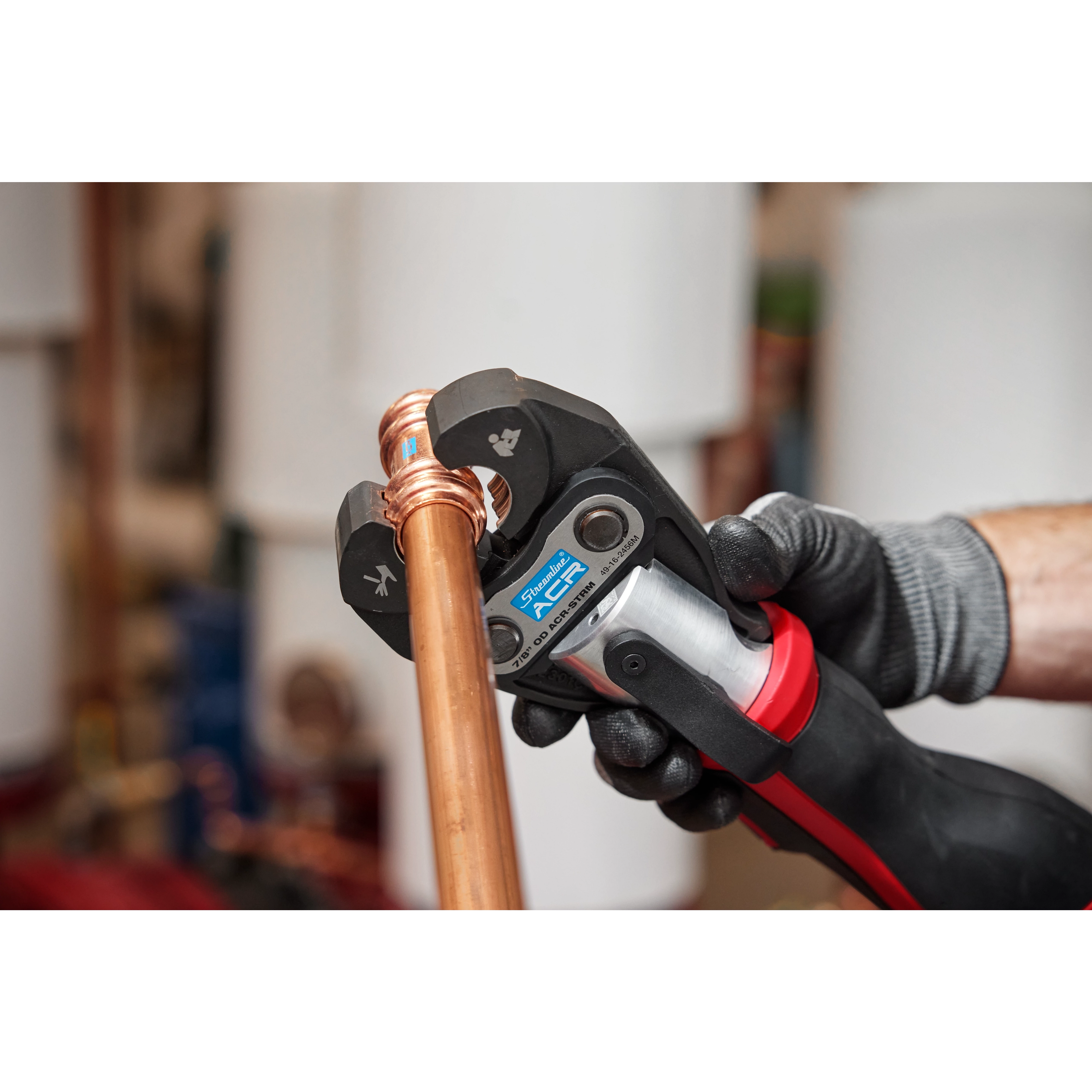 Worker using the Streamline ACR Press Jaw for M12 FORCE LOGIC Press Tool to crimp copper piping, wearing a black work glove.