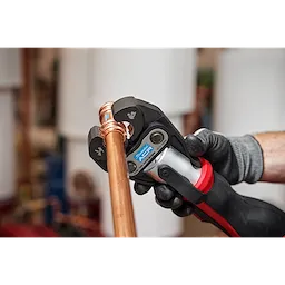 Worker using the Streamline ACR Press Jaw for M12 FORCE LOGIC Press Tool to crimp copper piping, wearing a black work glove.