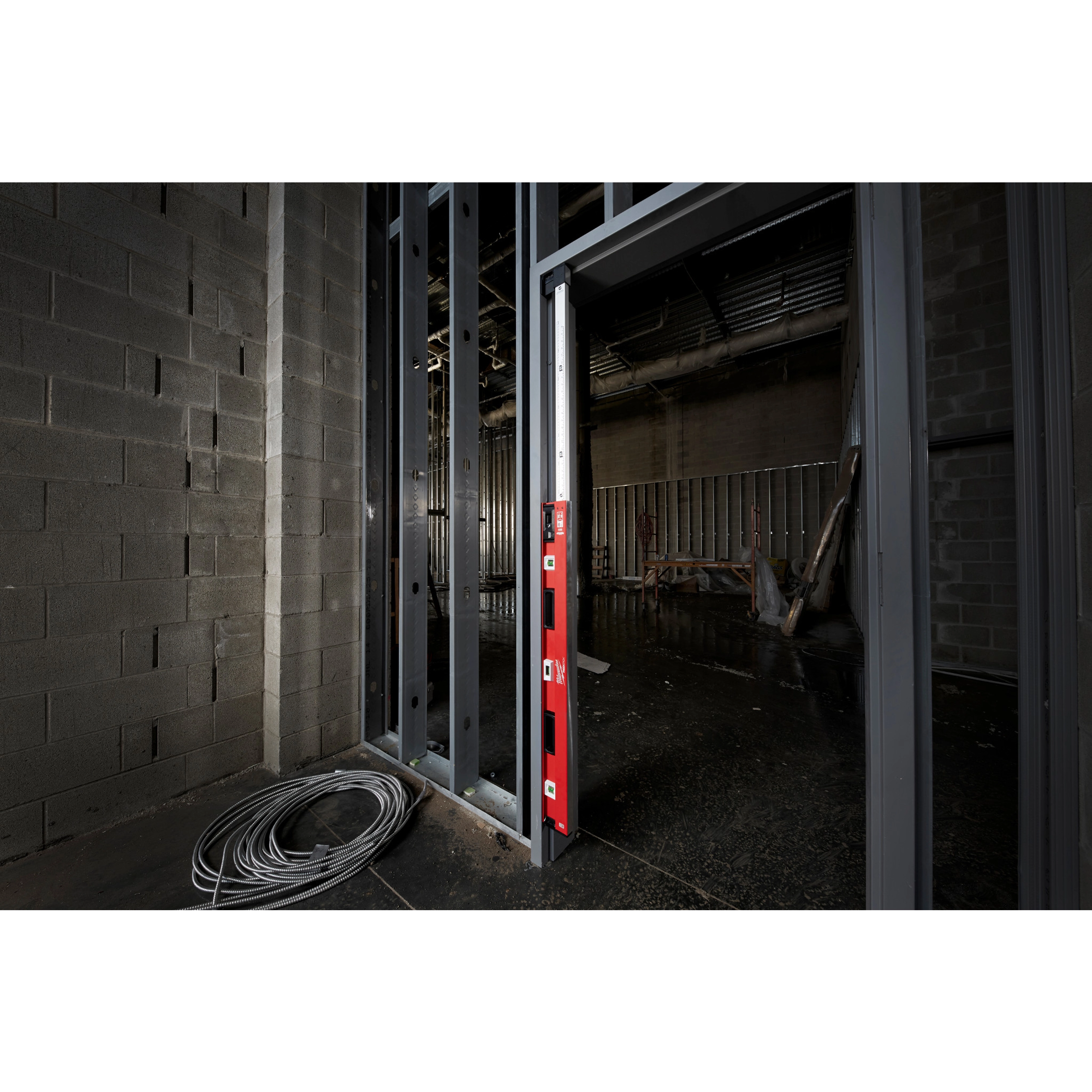 48"-78" Expandable Level in red and black placed against a metal stud frame in an unfinished construction site.
