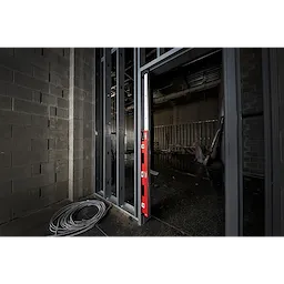 48"-78" Expandable Level in red and black placed against a metal stud frame in an unfinished construction site.