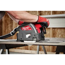 Milwaukee 6-1/2" 4T Fiber Cement Track Saw Blade being used by a person wearing red gloves to cut through fiber cement board.