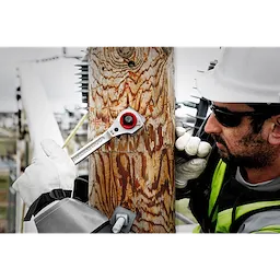 A worker uses the Lineman's 5in1 Ratcheting Wrench to secure a bolt on a wooden utility pole, displaying its effectiveness in outdoor conditions.