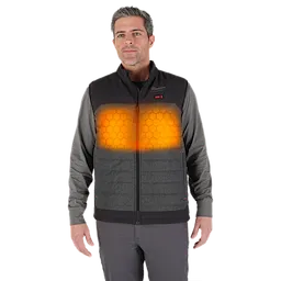A person is wearing an M12™ Heated AXIS™ Vest. The vest is black and grey, with a front zipper and glowing heating elements visible on the chest area. The individual is also wearing a long-sleeve grey shirt underneath the vest.