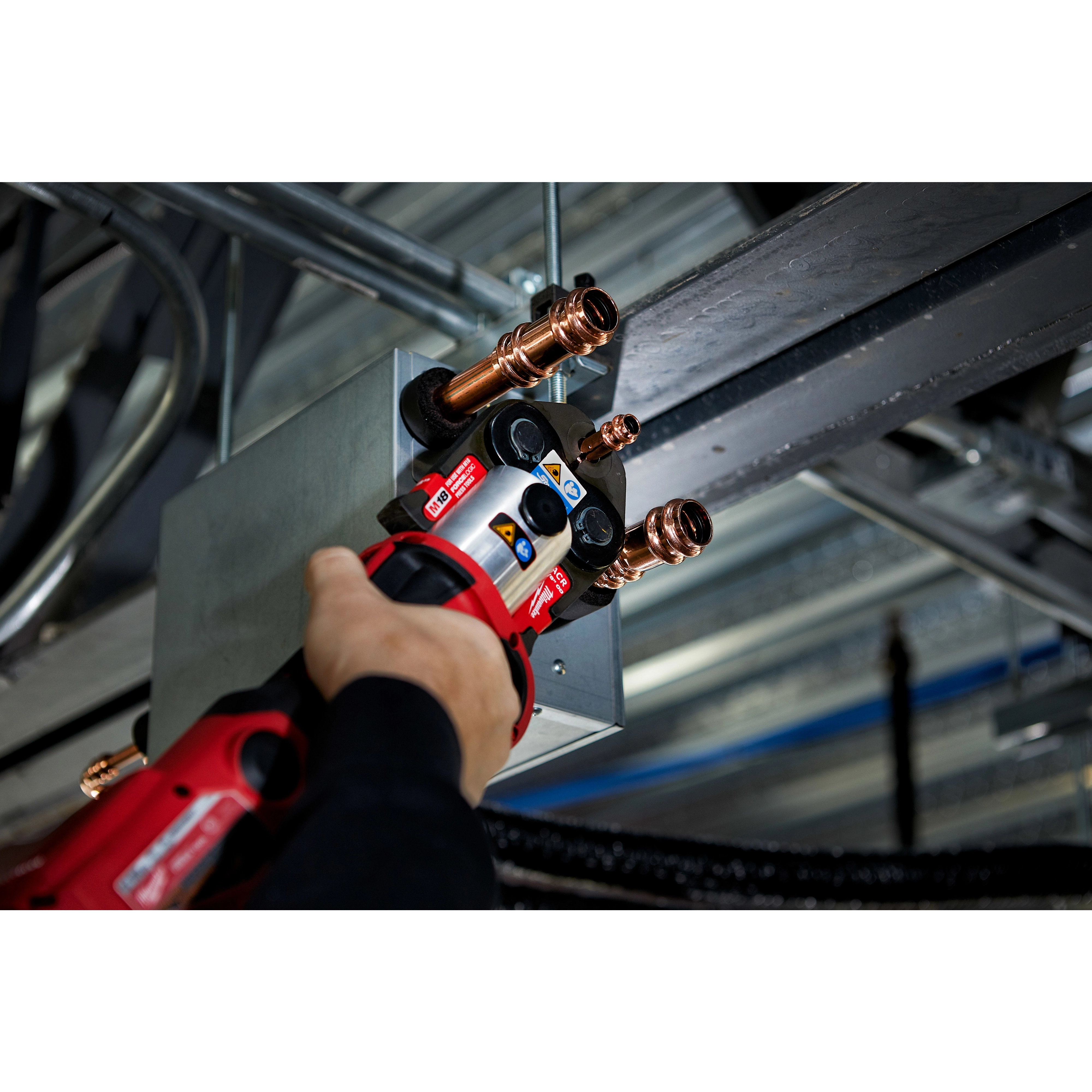Person using the M18 FORCE LOGIC Press Tool Kit with One-Key and 1/4"-7/8" Streamline ACR Jaws to press copper pipes.