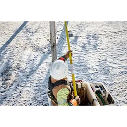 Worker using BOLT Personal Voltage Detector on a yellow pole to check electrical lines from a bucket truck in a snowy area.