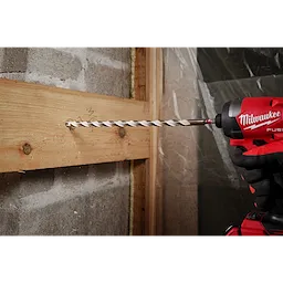 A 1/2" x 10" x 12" SHOCKWAVE Impact Duty Carbide Multi-Material Drill Bit being used to drill through a wooden board.