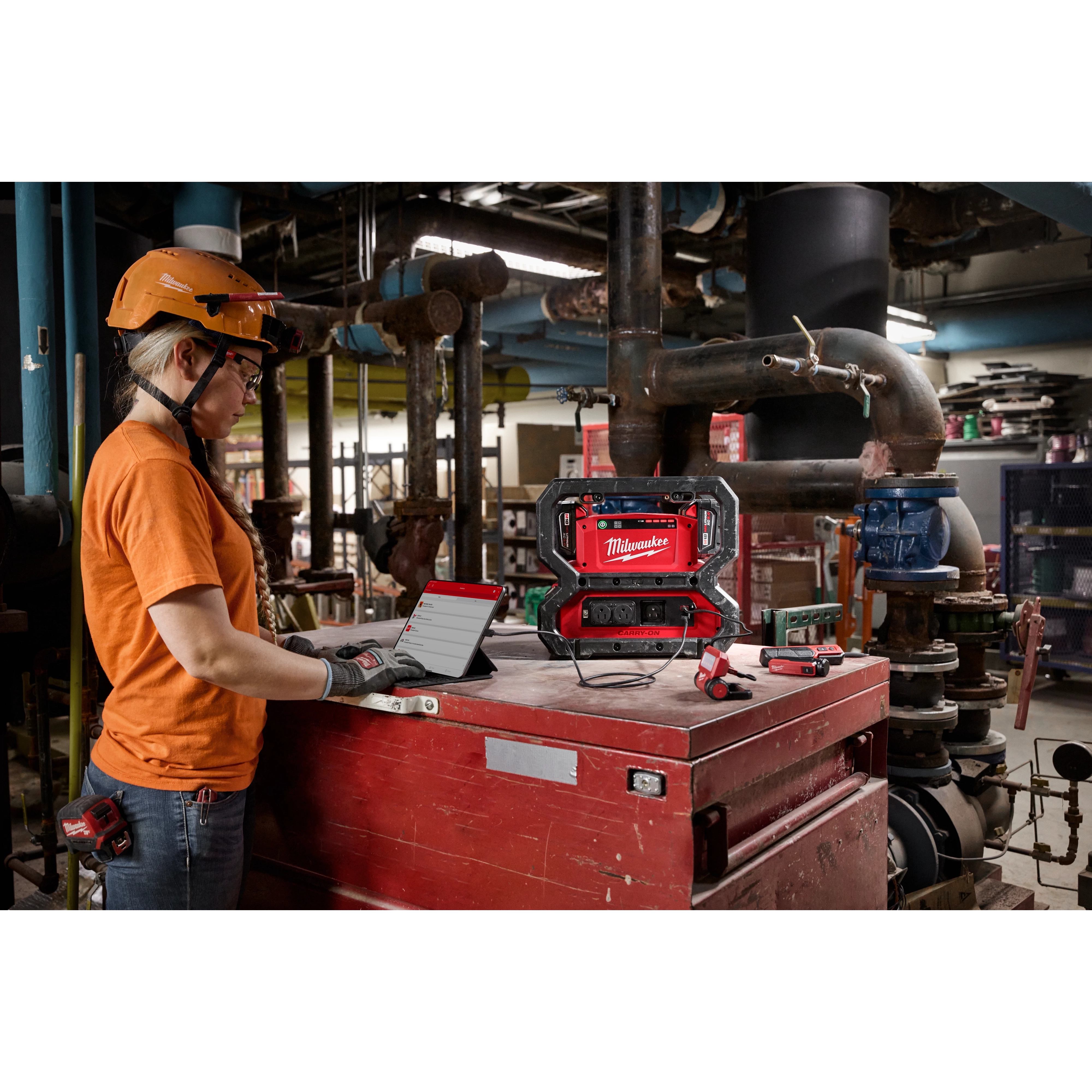Woman using the M18 Carry-On 3600W/1800W Power Supply to charge a tablet on the jobsite