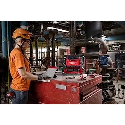 Woman using the M18 Carry-On 3600W/1800W Power Supply to charge a tablet on the jobsite