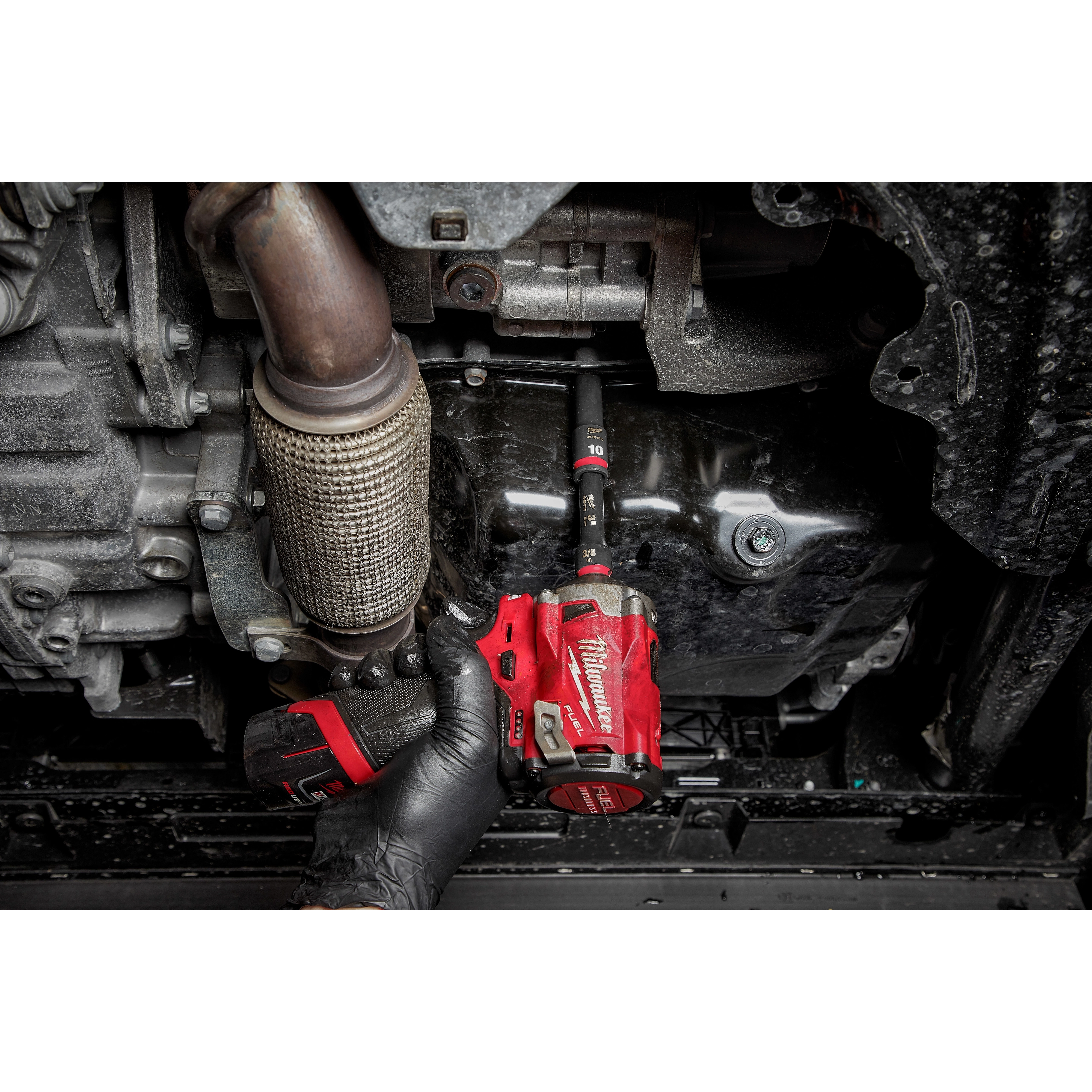 A gloved hand uses a red impact wrench with a SHOCKWAVE Impact Duty 3/8" Drive 10MM Deep 6 Point Socket to work on an automotive part.
