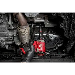 A gloved hand uses a red impact wrench with a SHOCKWAVE Impact Duty 3/8" Drive 10MM Deep 6 Point Socket to work on an automotive part.