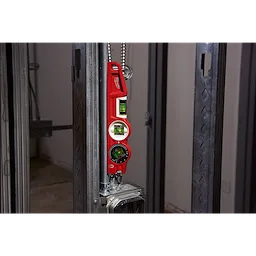 Red Block Torpedo Level attached to steel framing in a construction setting, showing three green vials for angle measurement.