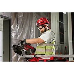 A construction worker wearing Vented Goggles - Clear Dual Coat Lens uses a red and black power tool while wearing protective gear.