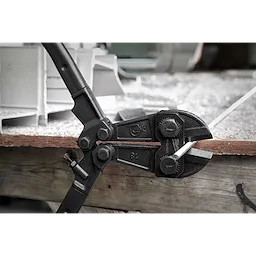 18" Bolt Cutter with black handles cutting a metal rod on a wooden workbench. The tool features two large bolts near the jaw.