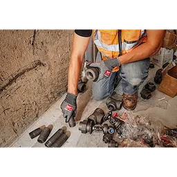 Technician wearing Cut Level 4 High-Dexterity Nitrile Dipped Gloves - XL handles pipes and fittings in a workshop setting.