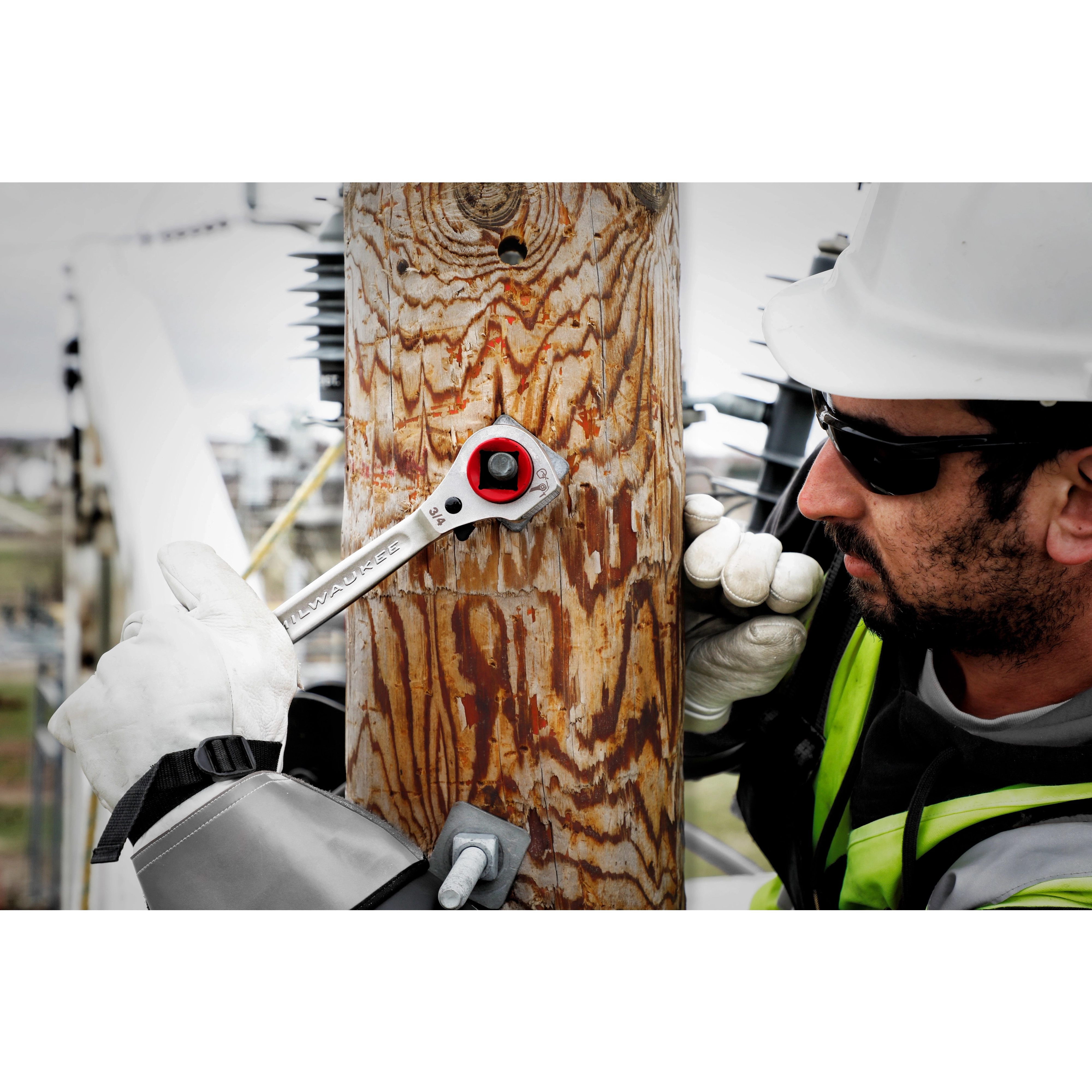 Lineman's 5IN1 Ratcheting Wrench w/ Milled Strike Face being used by a worker on a hook affixed to an outdoor utility pole.