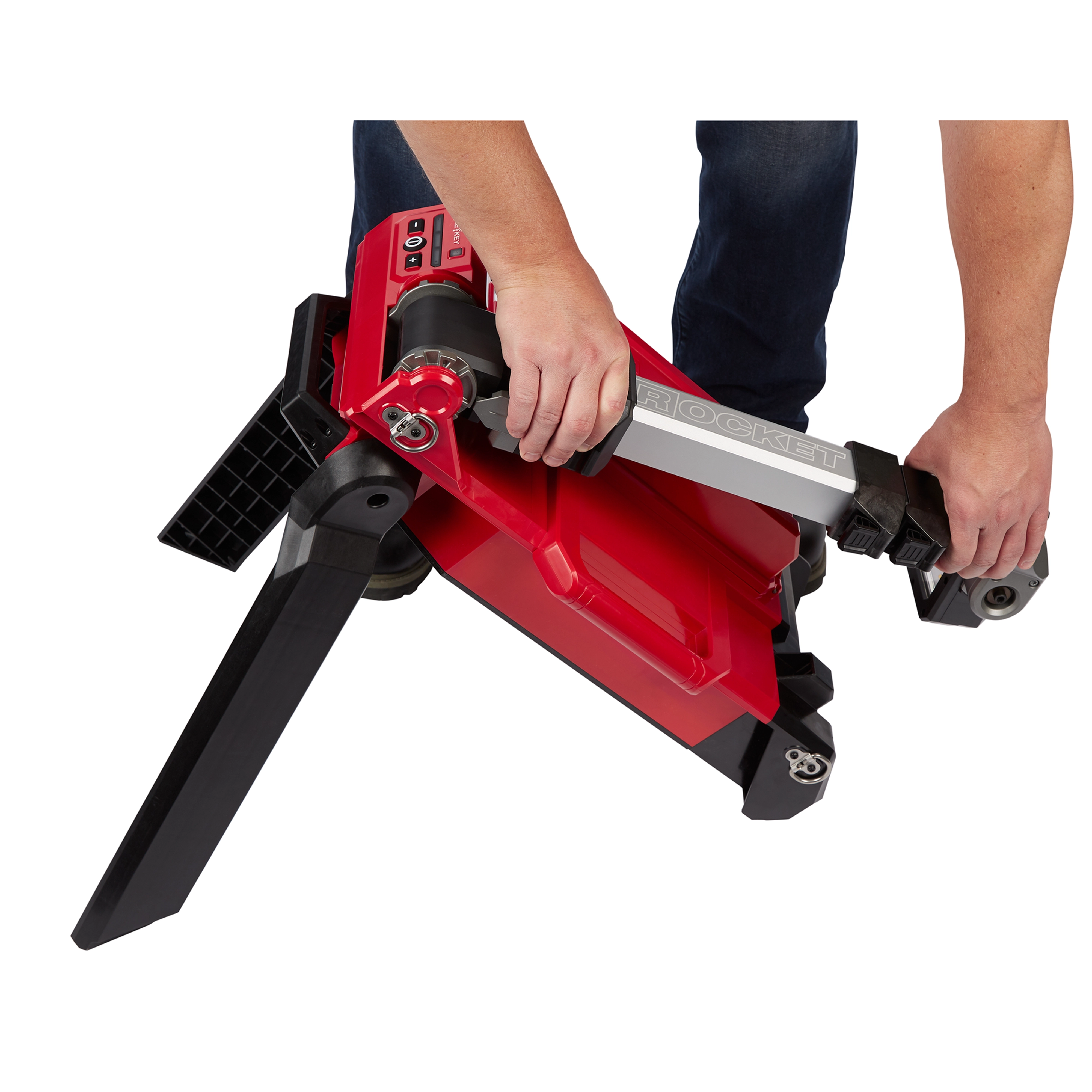 Person adjusting the tripod base of an M18 Rocket Light, featuring a red and black design, showing control buttons and grip handles.