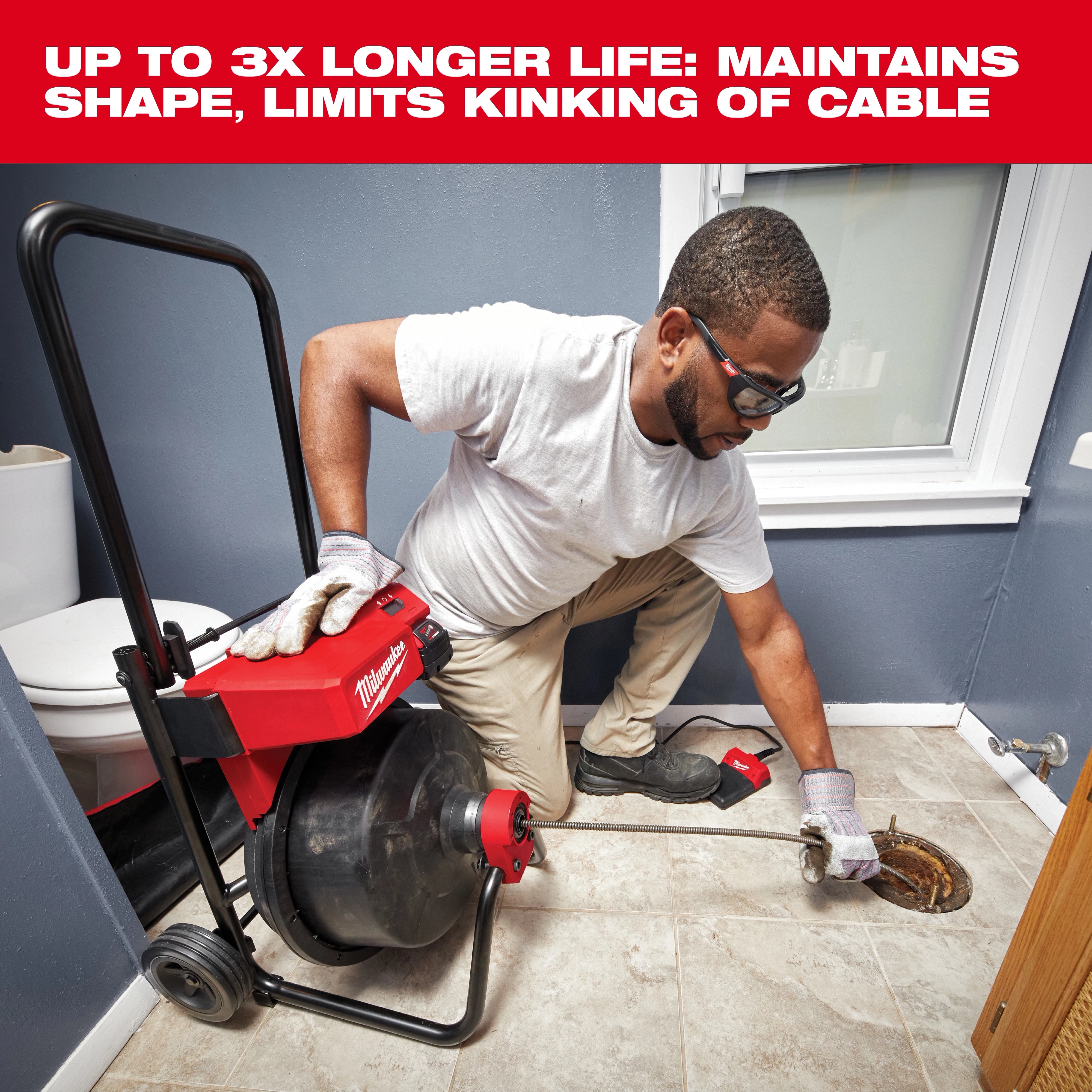 A person operates the Milwaukee drain snake tool in a bathroom, feeding the cable into a floor drain. The drain snake is mounted on a wheeled cart with cable storage and has a handle for ease of use. The text above reads, "Up to 3x longer life: maintains shape, limits kinking of cable."