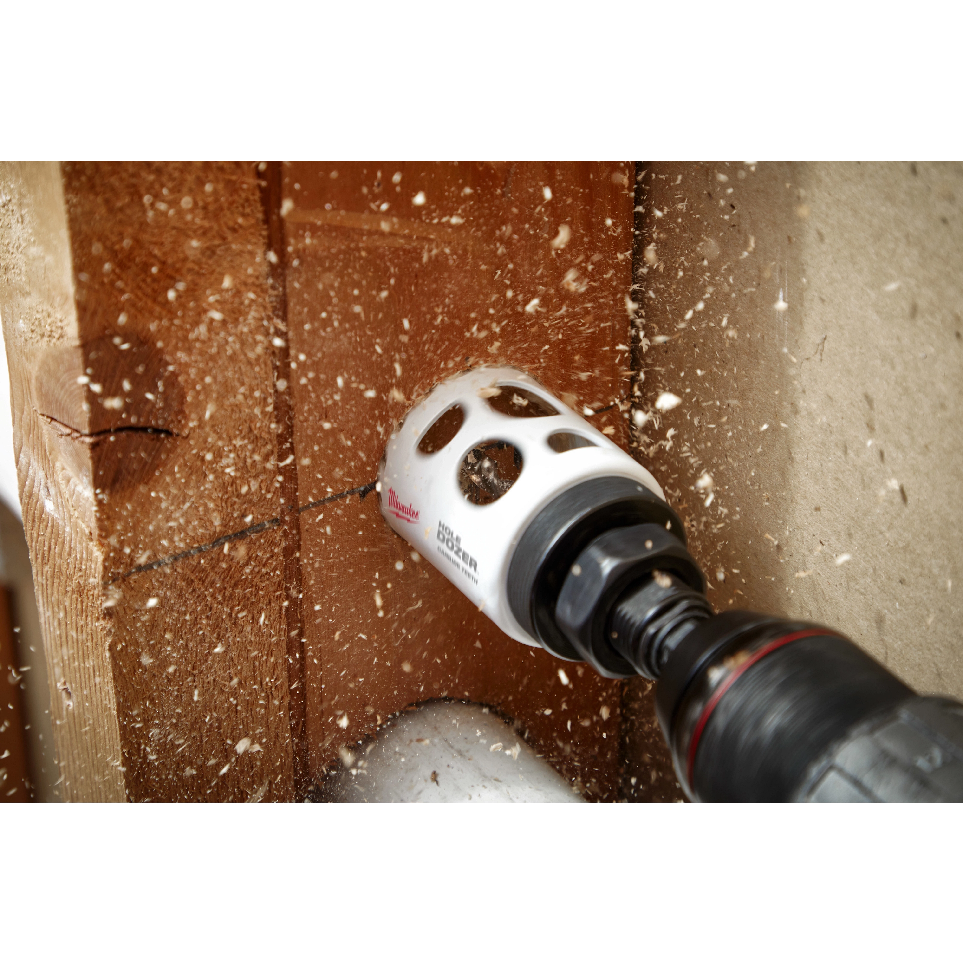 2" Hole Dozer with Carbide Teeth drilling through a wooden surface, creating sawdust and wood chips with a cordless power drill.